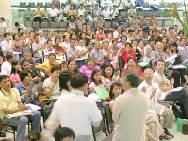 セブ市で開かれた比日系人会連合会総会。寺岡会長や河合弁護士(中央の後ろ姿)の説明に熱心に聞き入る参加者ら=12日午後2時10分ごろ写す