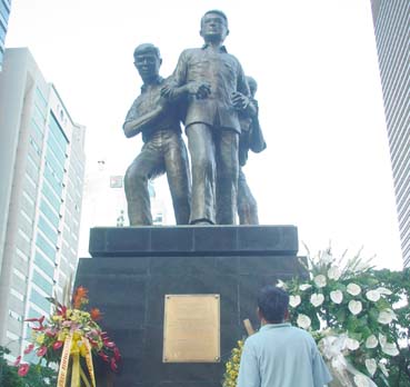 「フィリピン民主主義の象徴」、ベニグノ・アキノ氏像前に置かれた献花=マカティ市アヤラ通りで21日午後4時半ごろ写す