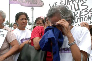 過去を思い出して涙をぬぐうメルカドさん=首都圏パサイ市の在比日本大使館前で14日午前11時半ごろ写す