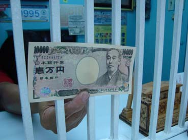 偽1万円札を見せる両替店の女性従業員=首都圏マニラ市で11日写す