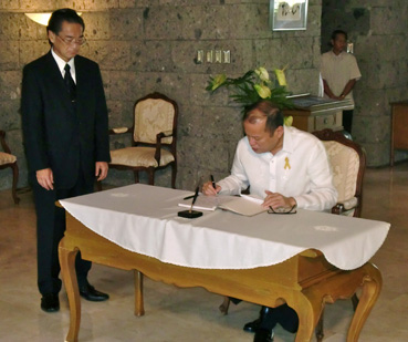 駐比日本大使公邸で記帳するアキノ大統領。左は桂大使=17日午前10時35分ごろ写す