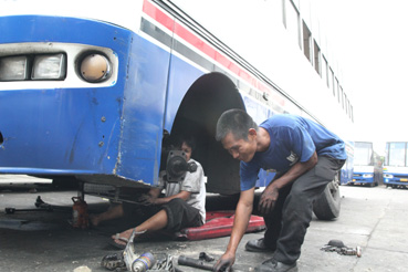 会社敷地内でバスを整備する従業員ら=24日午後2時ごろ、首都圏ケソン市で写す