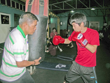 サンドバッグにパンチを撃ち込む大塚さん(右)と、コーチのカベサスさん=11月11日午後6時すぎ、首都圏ケソン市カティプナン通りのエロルデ・ジムで写す