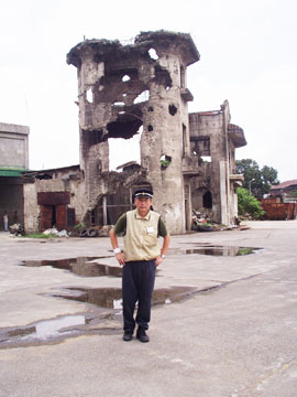 米軍の砲撃により廃虚となったブロックハウス。手前は学徒兵追悼の思いを込め旧制高校の白線帽をかぶる阿部孝雄さん