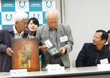 いとこが持参した写真を見る利光カズオさん(左)=17日午後5時55分、東京都港区の日本財団で写す