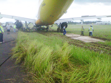 草地がぬかるんだため、後輪部分に鉄板を敷きながら事故機を前進させる作業が続いた=セブパシフィック航空提供