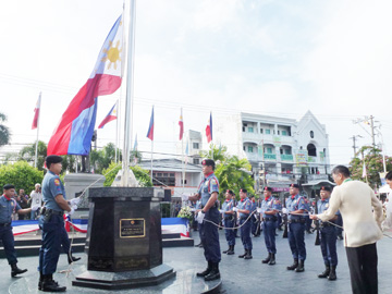 アギナルド初代大統領の銅像前で国旗を掲揚するオチョア官房長官=12日午前8時ごろ、ルソン地方ブラカン州マロロス町のバラソアイン教会で写す