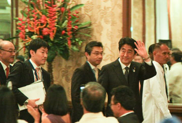 手を挙げながら、比日功労賞授与式会場を出る安倍首相=26日午後9時50分ごろ、首都圏マカティ市で写す