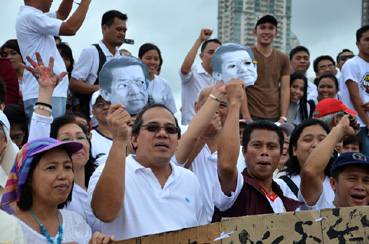 8月下旬の抗議集会で、大統領の亡父ベニグノ元上院議員の面を掲げてポークバレル全廃を訴える参加者ら