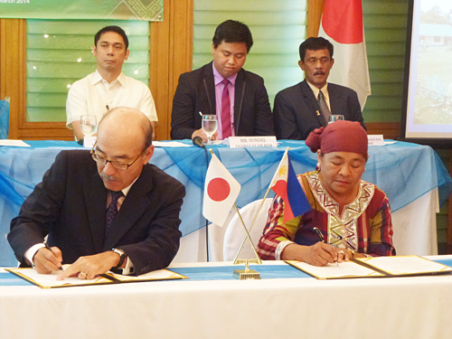 無償資金協力事業の調印書に署名する卜部敏直駐比日本大使(左)=20日午前10時半ごろ、首都圏パシッグ市で写す