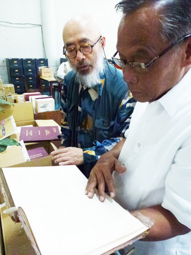米国の比における植民地政策について1890年代末に書かれた本を眺める津田教授(左)とターリット館長=2月28日午前10時ごろ、首都圏ケソン市の比大ディリマン校で写す