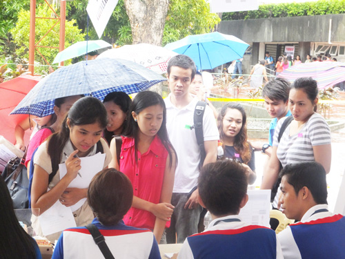 雨の中、面接の順番を待つ求職者ら=12日午後1時半ごろ、首都圏マニラ市リサール公園で写す