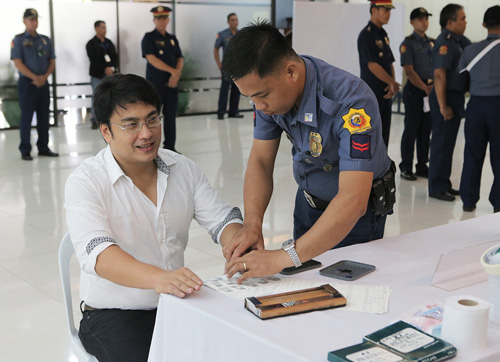 国家警察本部に移送後、笑顔を見せながら指紋採取に応じるレビリア議員=国家警察提供