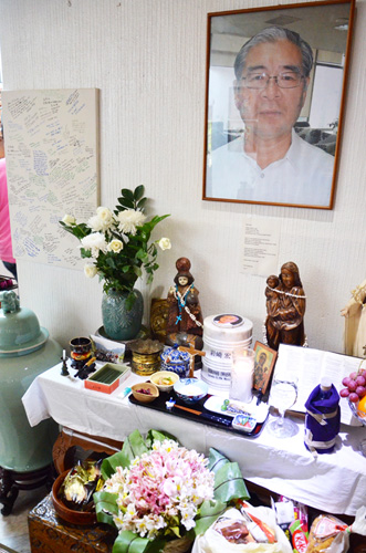自宅内に安置された岩崎さんの遺影と遺灰。霊前には1日3回、食事が供えられ、傍らには友人らの寄せ書きも