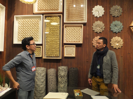 来客に商品の特徴を説明する佐久間航さん(右)=17日午後3時半ごろ、首都圏パサイ市の展示会場で写す