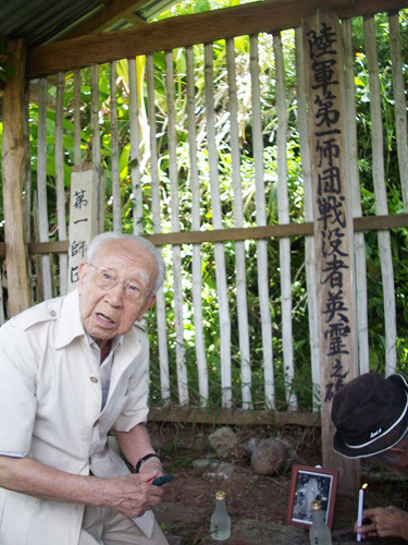 激戦の地、リモン峠の第一師団の慰霊碑。蔓草と雑草を取り払ったあと、松本さんは靖国神社のお神酒、浅草の観音様の写真を添え、戦友の霊に深々と頭を下げた