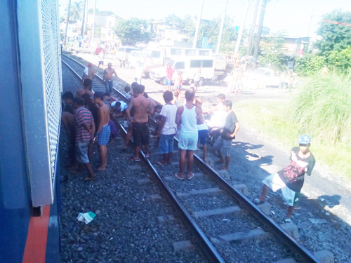 列車にはねられた男性を取り囲む沿線住民ら=20日午前8時10分ごろ写す