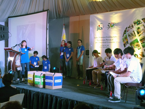 記念式典の舞台でそれぞれの事業を紹介する青年海外協力隊員=22日午後8時ごろ、首都圏マカティ市で写す