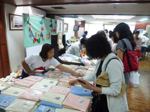 バザーに並んだ商品を見る買い物客=22日午後1時ごろ、首都圏マカティ市で写す