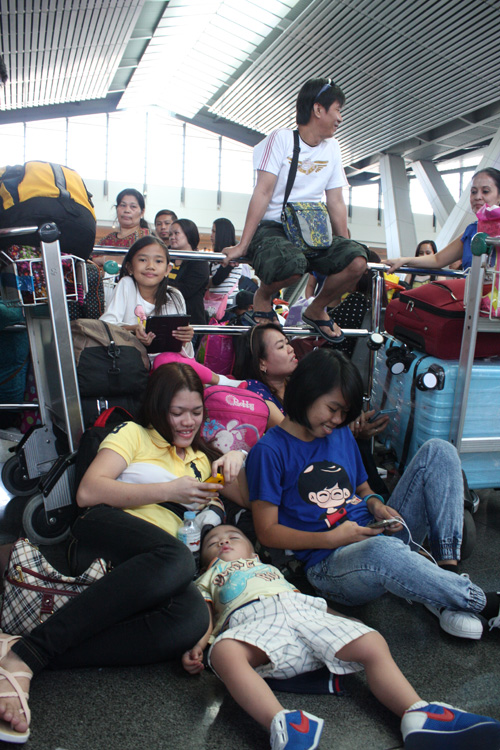 欠航でターミナル内に足止めされ、床に座り込む空港利用客=3日正午ごろ、マニラ空港第3ターミナルで立田成美写す