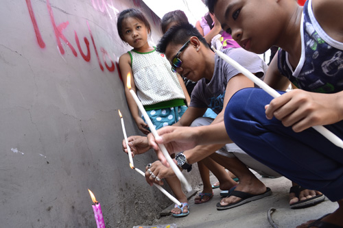火災現場となった工場の前でろうそくを立てる遺族ら=13日午前10時半ごろ、首都圏バレンスエラ市で加藤昌平写す