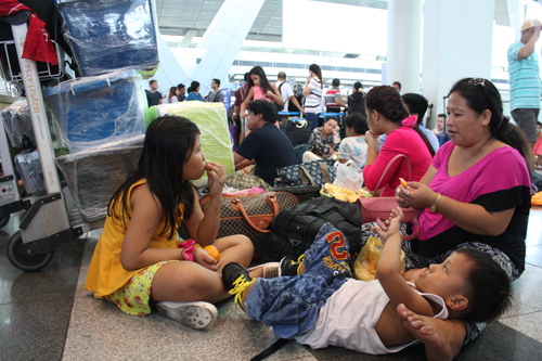 4月に発生した長時間停電の際に、ターミナルで待機する比人旅行客の家族。荷物は銃弾所持事件に巻き込まれないようラップで包装されている。=マニラ空港第3ターミナルで立田成美写す