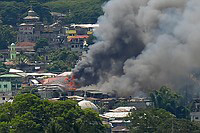 18日、フィリピン南部ミンダナオ島マラウィ市で、空軍がイスラム過激派の拠点を空爆し、白煙が立ち上る様子(AFP=時事)
