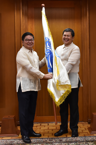 就任に際し、テタンコ前総裁から中銀の旗を受け取るエスピニリア新総裁=フィリピン中央銀行提供