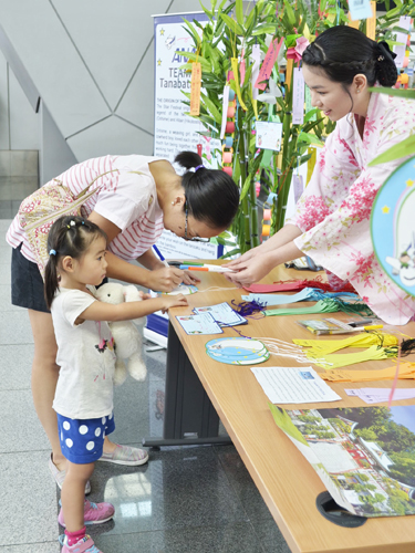 家族連れの旅行客も願い事を短冊に書き込んだ=7日正午ごろ、マニラ空港で伊藤明日香撮影