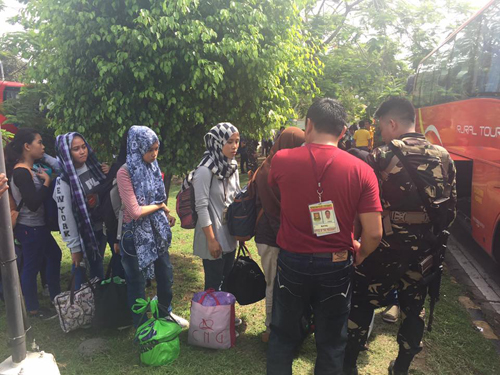 ミンダナオ州南ラナオ州マラウィ市内の大学に向かうため北ラナオ州イリガン市で国軍の護衛の下、バスに乗り込む学生ら=ミンダナオ州立大学提供