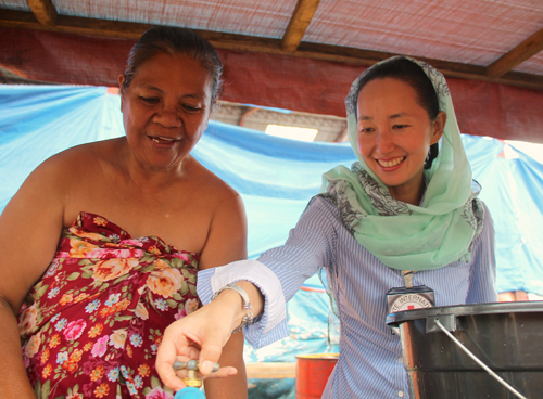 避難民の女性に赤十字が設置した手洗い場の状態について聞く松沢さん=11日午後、ミンダナオ地方南ラナオ州サギアラン町で冨田すみれ子撮影