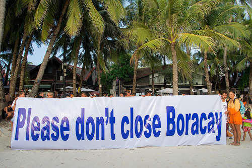 「ボラカイを閉鎖しないで」と、浜辺清掃活動後に横断幕を掲げて訴える地元市民団体=市民団体ボラカイユナイテッド提供