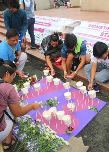 「73」の文字の上に献花し、ろうそくをともす集会参加者=14日午後4時半ごろ、首都圏パラニャーケ市のバクララン教会で冨田すみれ子撮影