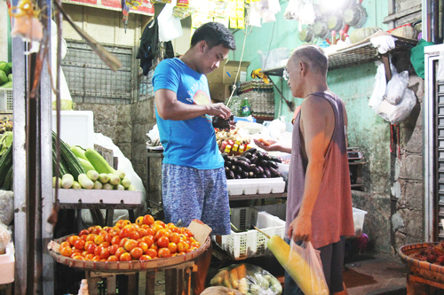 市場で野菜を買い求める男性。インフレと台風被害で野菜も大幅に値上がりしている=5日午後6時ごろ、首都圏マカティ市で冨田すみれ子