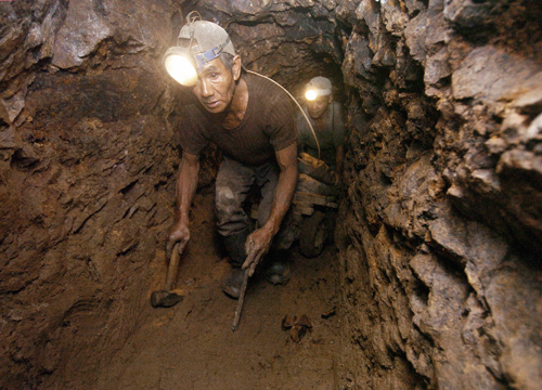 泥だらけになりながら坑道内を進む鉱山労働者=ルソン地方ベンゲット州イトゴン町の鉱山で2006年撮影(AFP=時事)