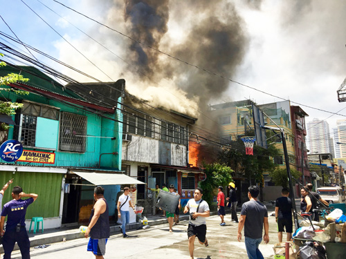 激しく煙が上がる中、駆け出す住民ら=28日午後0時半ごろ、首都圏マカティ市ピオ・デル・ピラールで森永亨撮影