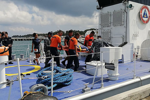 転覆したドラゴンボートから救助され運ばれる男性(AFP=時事)