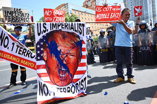 6日、首都圏の米大使館前でトランプ大統領の顔写真にペンキを塗り、米国によるイラン司令官殺害に抗議する人々(AFP=時事)