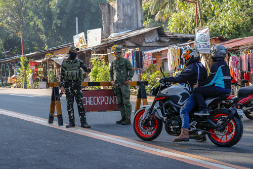 首都圏などの防疫措置である一般防疫地域(GCQ)が10月31日まで延長された。リサール州タナイ町の検問所で車両やバイクの検問をする国軍兵士ら=9月29日撮影(EPA=時事)