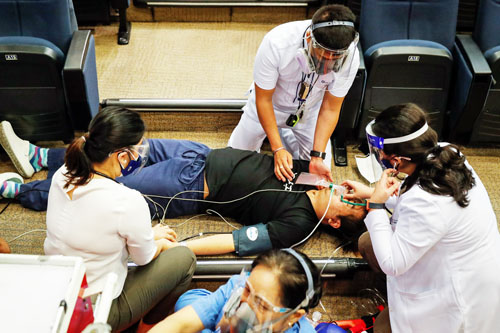 医療従事者のワクチン接種訓練で副反応で倒れたふりをする男性ら=首都圏パシッグ市のメディカルシティー病院(EPA=時事)