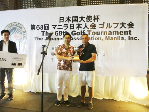 越川大使(左)から大使杯を受け取る優勝者の塚本秀幸さん(右)=マニラ日本人会提供