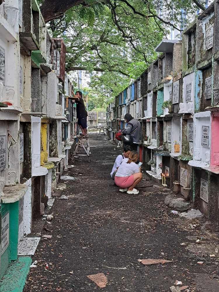 マカティ市にあるマニラ南部墓地では墓参者がまだ少ないものの、ちらほらとお参りに訪れたり、墓地を清掃する人たちがいた=29日午後1時半ごろ、澤田公伸撮影