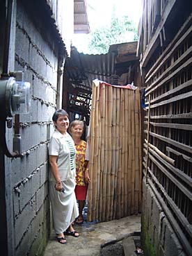 竹でできた自宅玄関に立つアギラさん(右)。左は軍医の2女サレナスさん