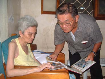 日本を初めて訪れた時の写真を見る中山さん(左)。戦争中、病院職員として徴用され「日本政府は私たちが生きている間に未払い分の給与を払って欲しい」と訴える