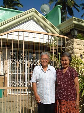 5年ほど前に新築された長男宅前に立つ甲斐さん(左)。長男は10年前から現在まで日本出稼ぎ中だ