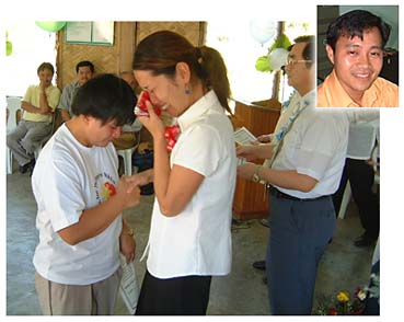 第35期研修終了式で日本語教師のボランティア女性と別れの握手を交わす日系3世の男性(左)・2002年11月30日、パンガシナン州で写す(顔写真はオステロ会長)