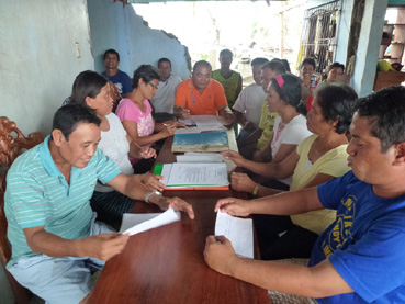 高潮で壁が大破した議長宅でバランガイ議会を開く議長のディソンさん(中央)と議員ら=12月22日午後0時半ごろ、ビサヤ地方サマール州バセイ町で写す