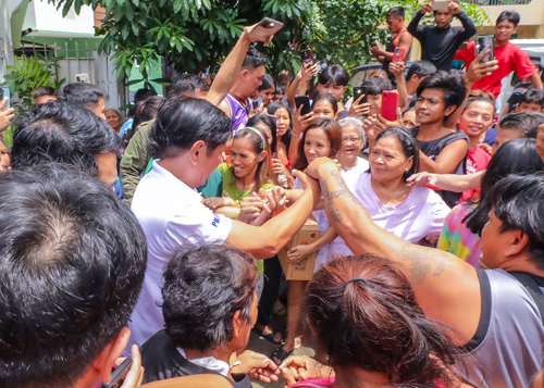 リサール州の避難所で救援物資を受け取った住民と話すマルコス大統領=26日、リサール州サンマテオ小学校(大統領府提供)