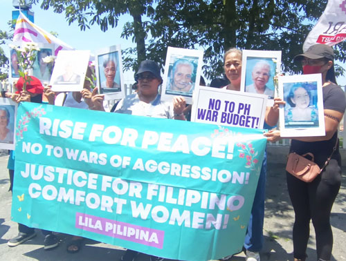 元慰安婦の遺影を持って抗議集会に参加した遺族ら=14日首都圏マニラ市ロハス通りで竹下友章撮影